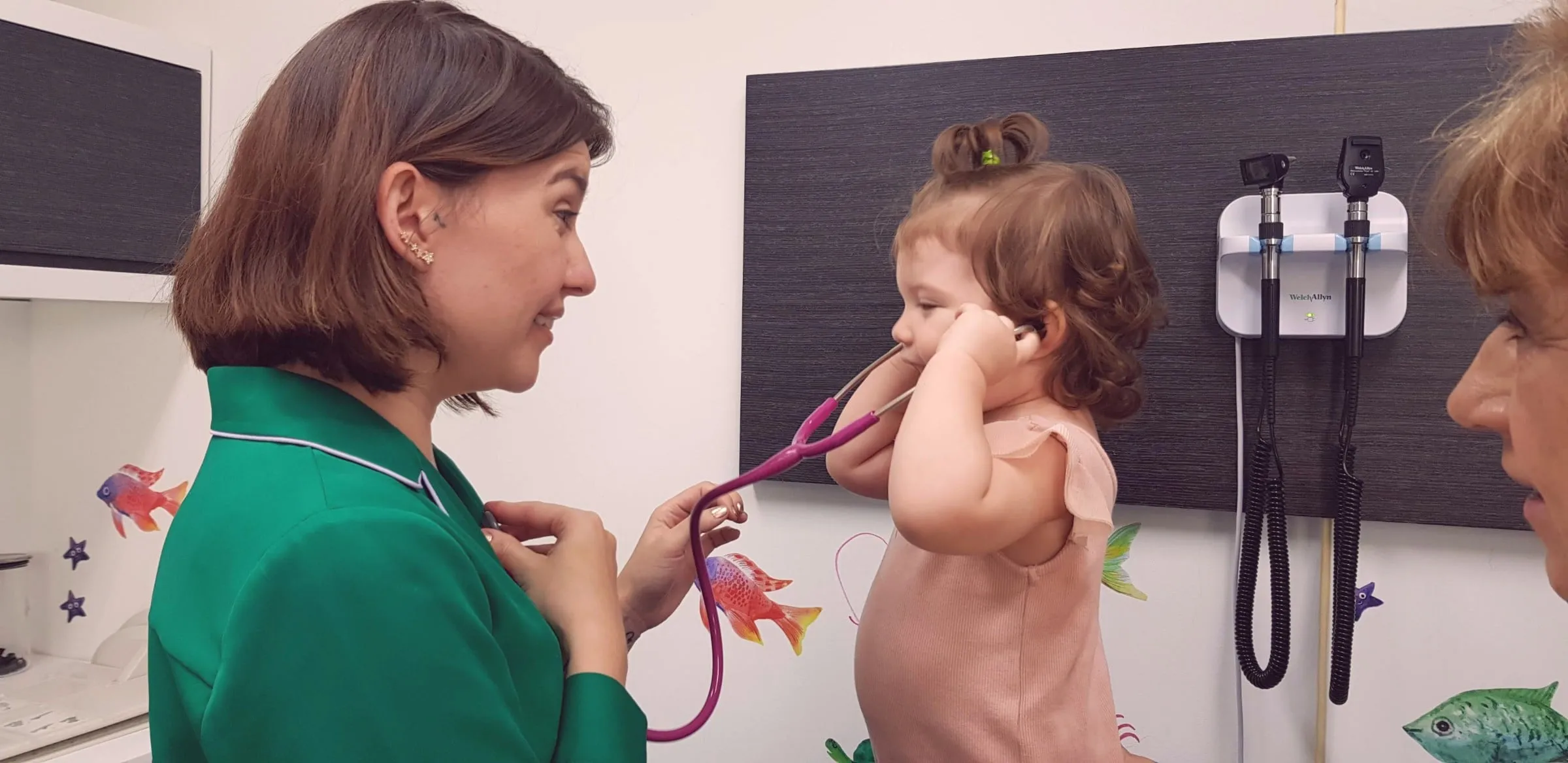 Una niña escucha con el estetoscopio a la pediatra durante la consulta