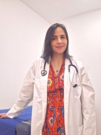 Dr. María Camila Echavarría standing in her office, wearing a white coat and stethoscope